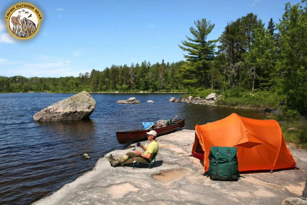 a man enjoying the view and camping on the lake shore with his kayak/canoe