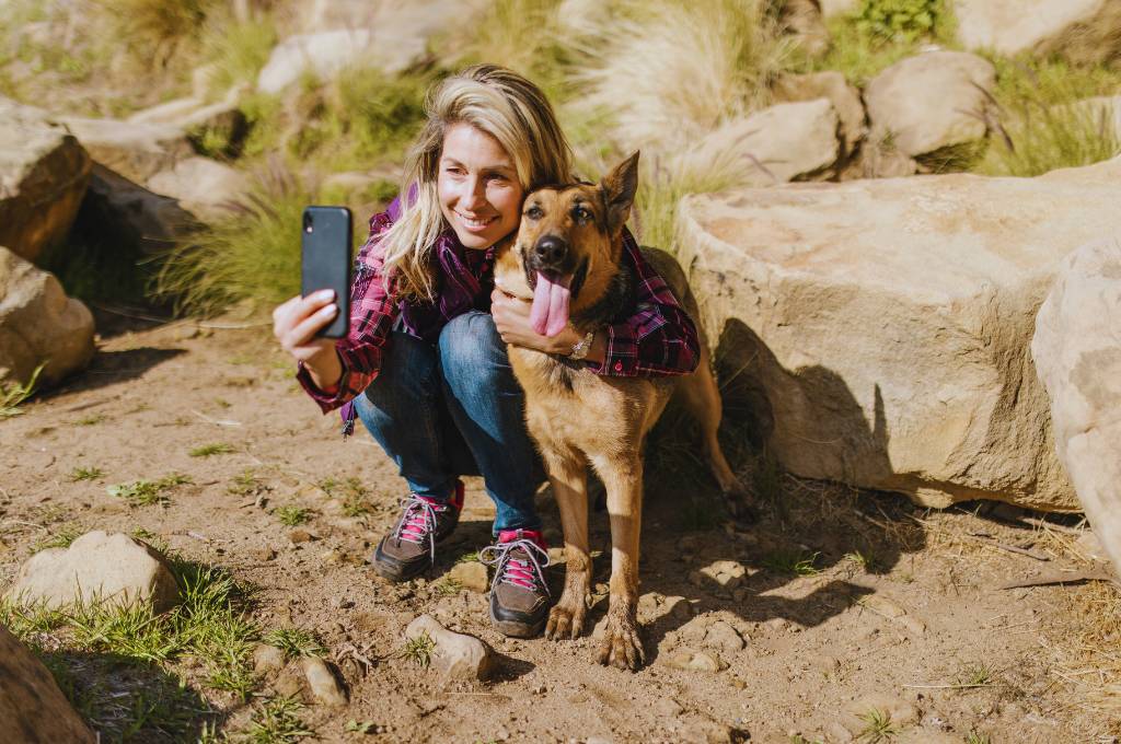 a woman taking picture with her dog during hike