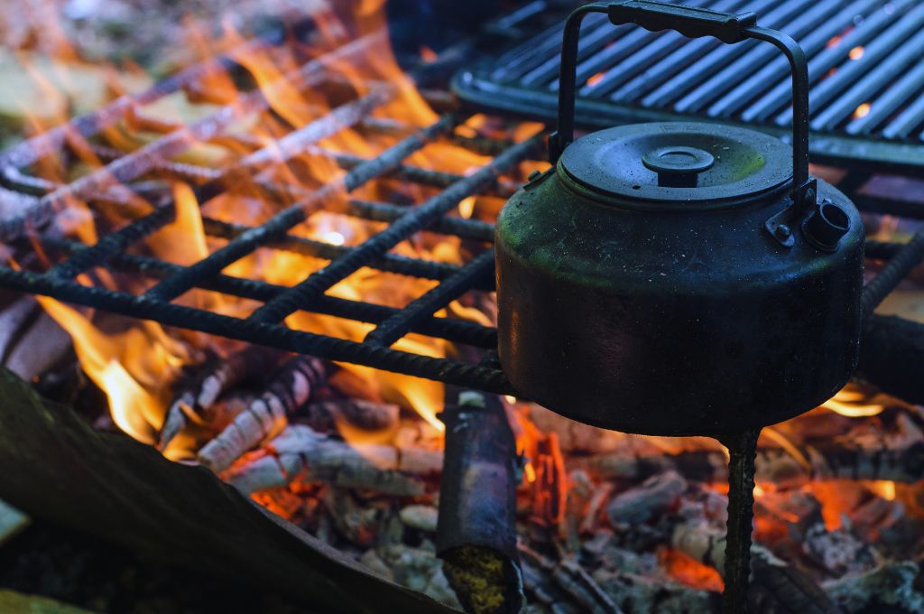 grills along with a pot on the campfire